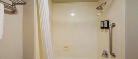A shower area with a bathtub, a handrail, and a towel rack.