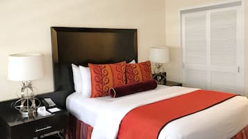 A hotel room with a large bed, a nightstand with a lamp, a phone, and a drawer.