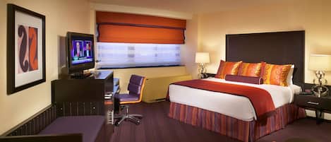 Een hotelkamer met een groot bed, een bureau met stoel, een televisie en een raam met uitzicht.