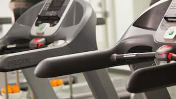 Un gimnasio con cintas de correr y una pantalla digital.