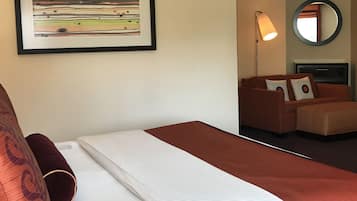 Een hotelkamer met een bed, een bank, een ronde spiegel en een kunstwerk in een lijst aan de muur.