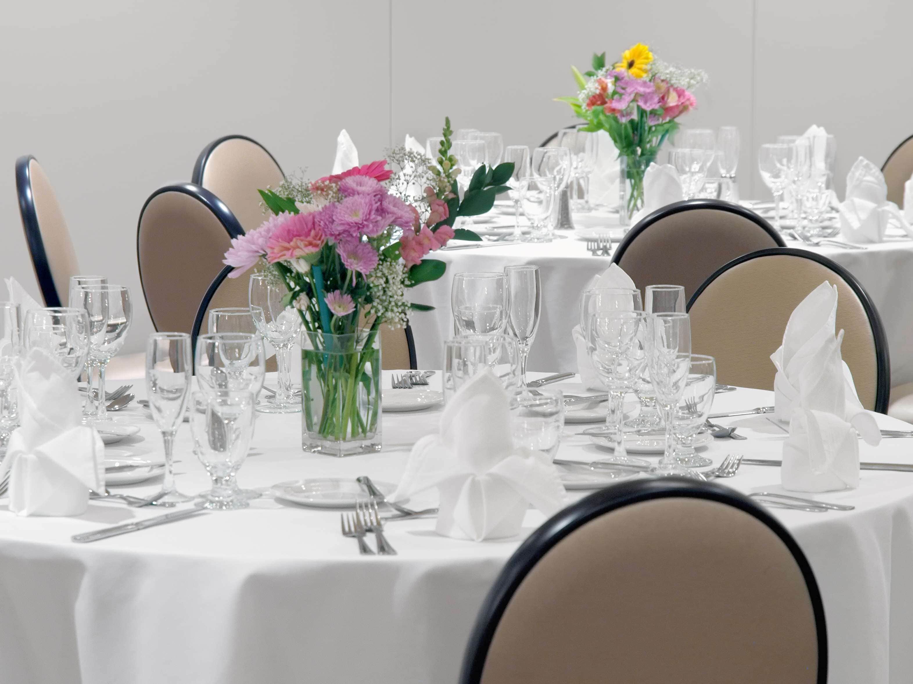 A banquet table set with white tablecloths, clear glassware, and floral centerpieces.