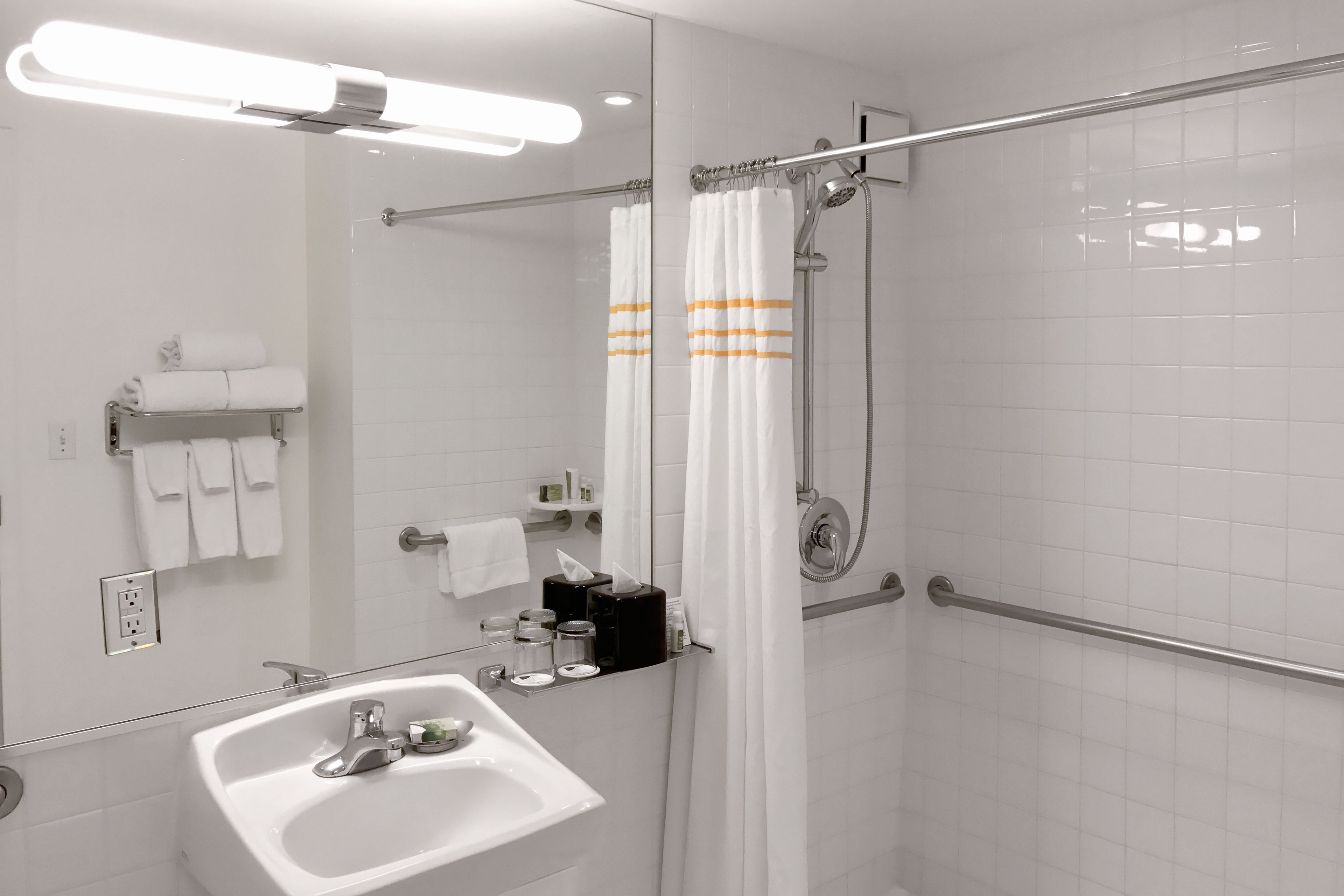 A modern bathroom with a white sink, mirror, and shower area.