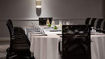 A conference room with a long table set for a meeting, equipped with chairs, water bottles, and glasses.