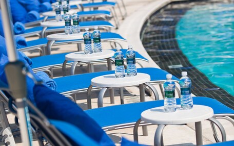 A poolside area with lounge chairs and tables, each with a bottle of water.