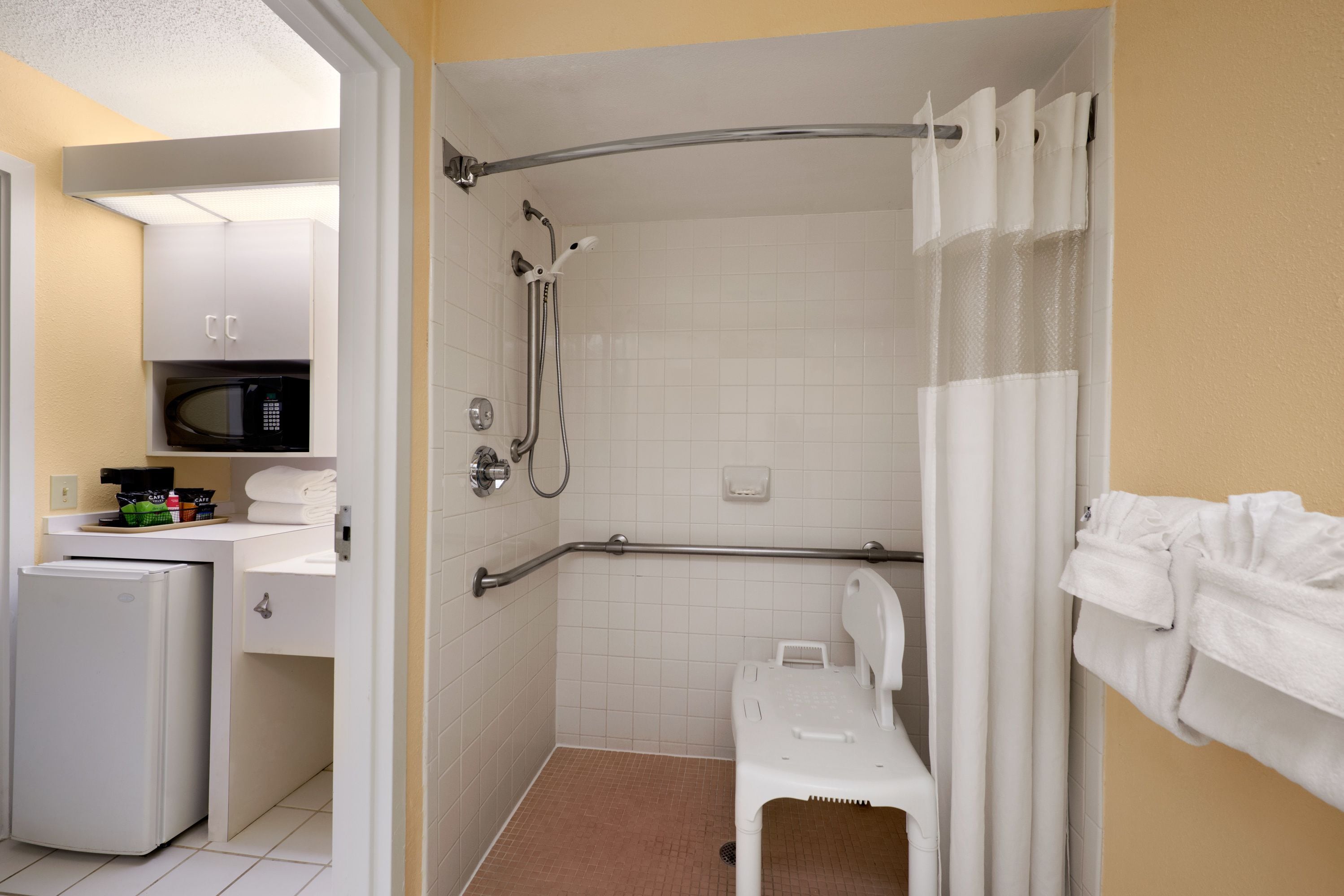 A compact bathroom with a shower, toilet, and a microwave.