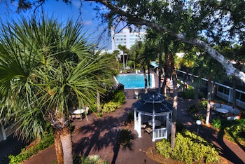 A hotel with a sandy courtyard, multiple balconies, and a blue umbrella structure. at Ramada by Wyndham Kissimmee Gateway