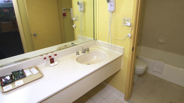 Un bagno con lavandino, specchio e due asciugacapelli montati a parete.