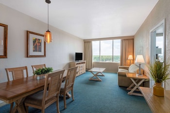 A hotel room with a large bed, a desk, a sofa, and a view of the city. at Ramada by Wyndham Kissimmee Gateway