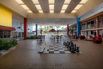 A pool area with a gazebo, palm trees, and a building in the background. at Ramada by Wyndham Kissimmee Gateway