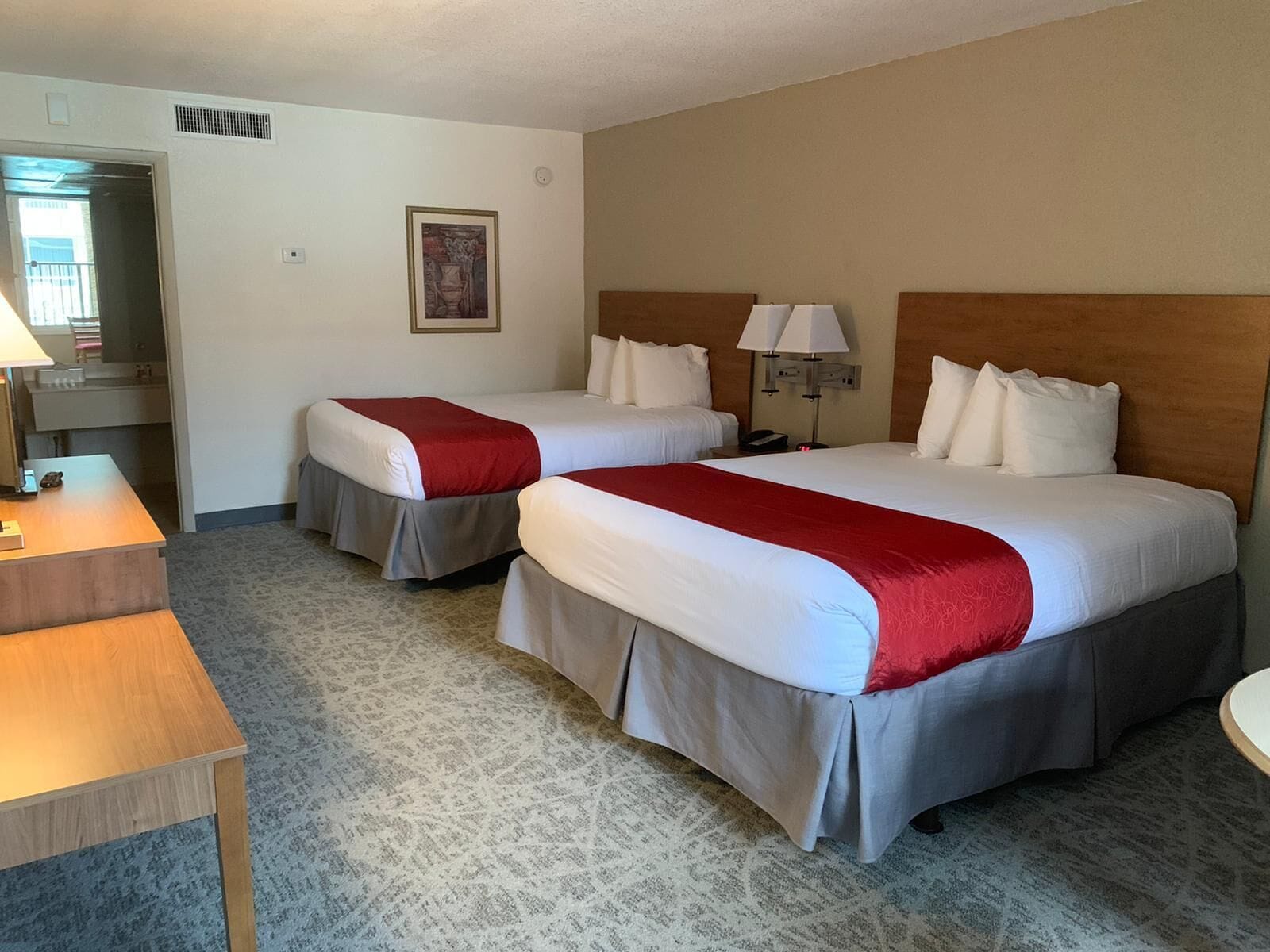 Quarto de hotel com duas camas, uma escrivaninha e uma cadeira.
