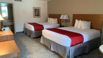 Quarto de hotel com duas camas, uma escrivaninha e uma cadeira.