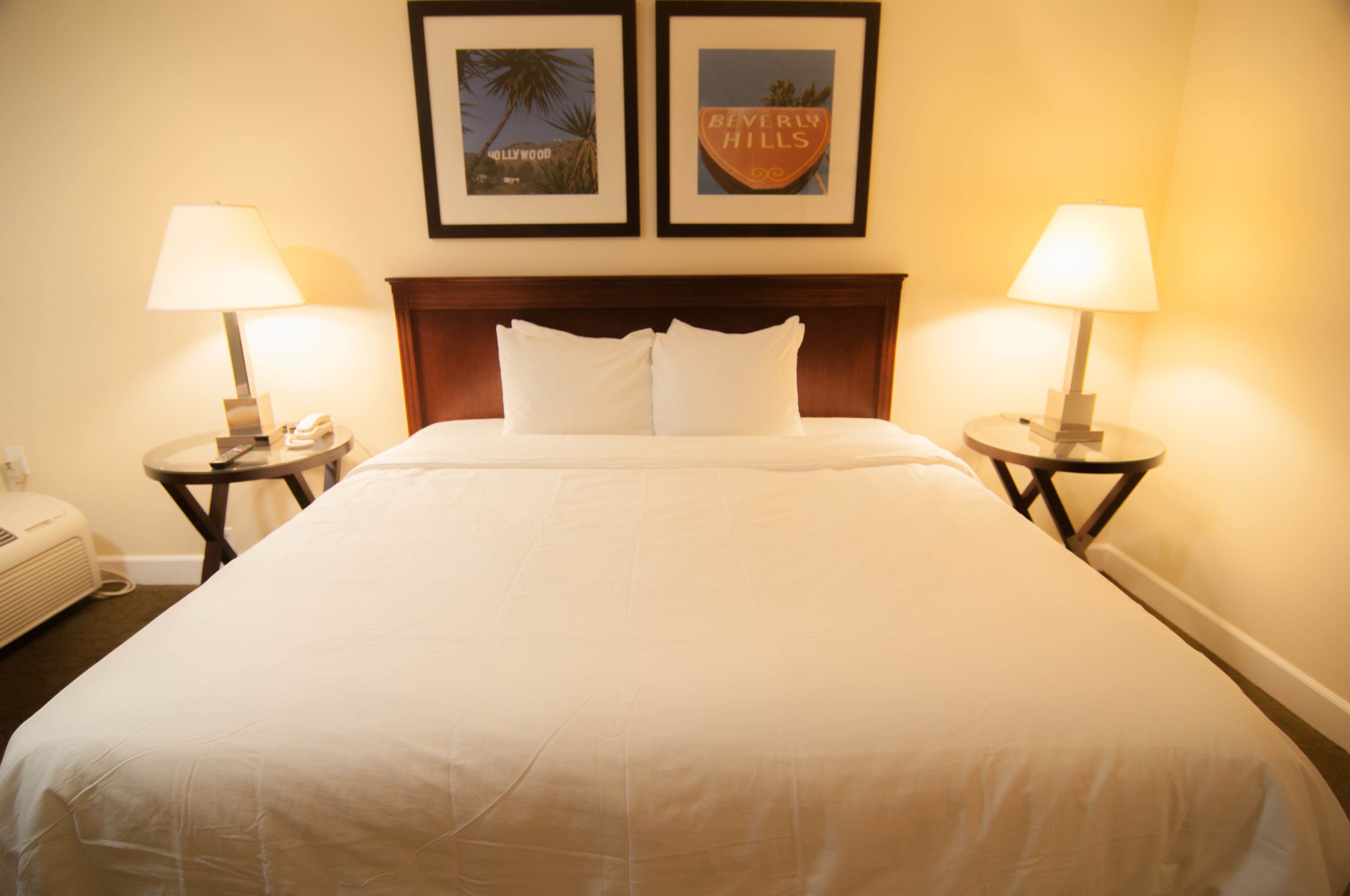 A hotel room with a large bed, two bedside tables with lamps, and two framed pictures on the wall.