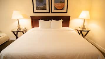 A hotel room with a large bed, two bedside tables with lamps, and two framed pictures on the wall.