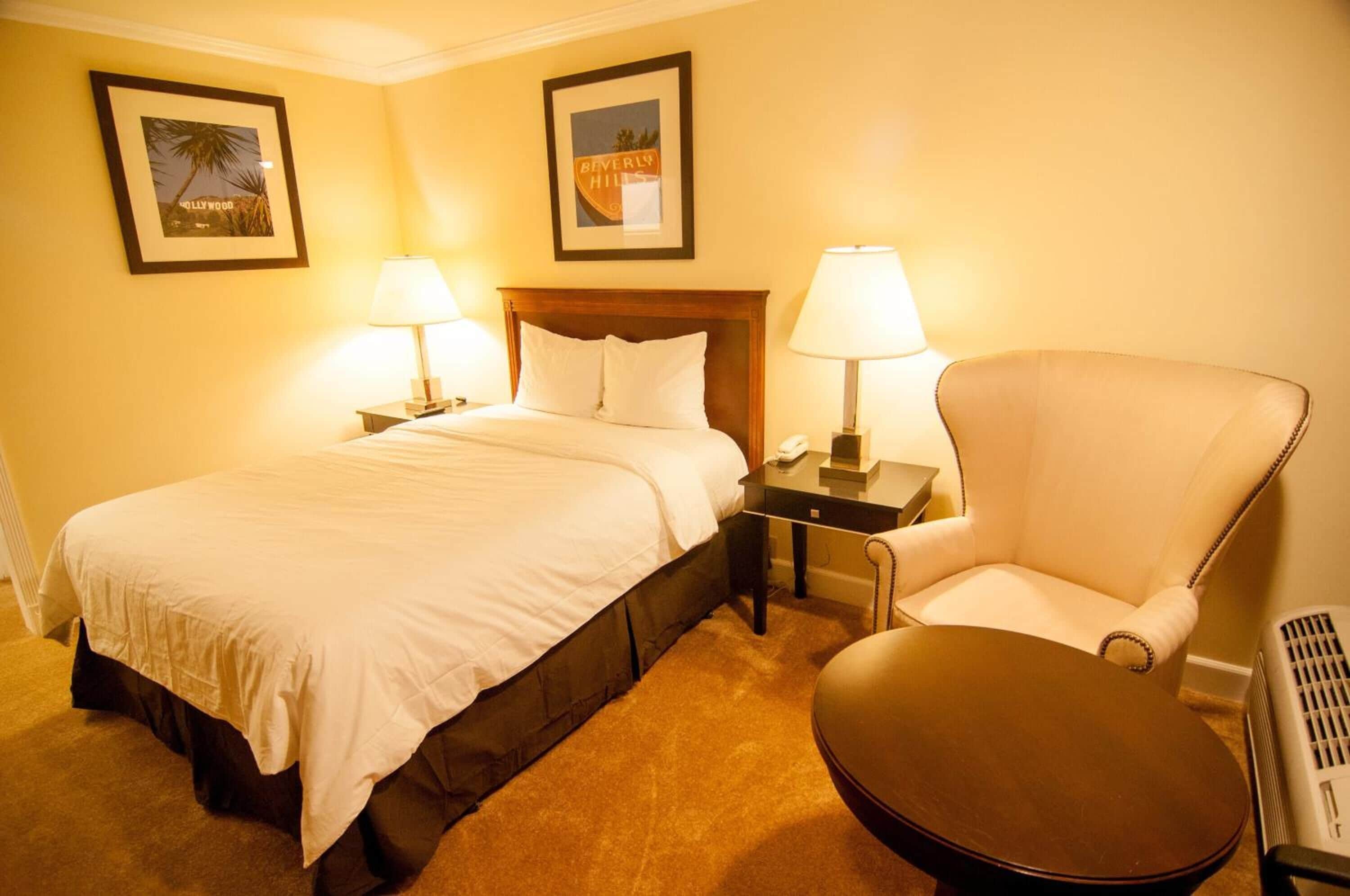 A hotel room with a bed, two bedside tables with lamps, a chair, and a small table.