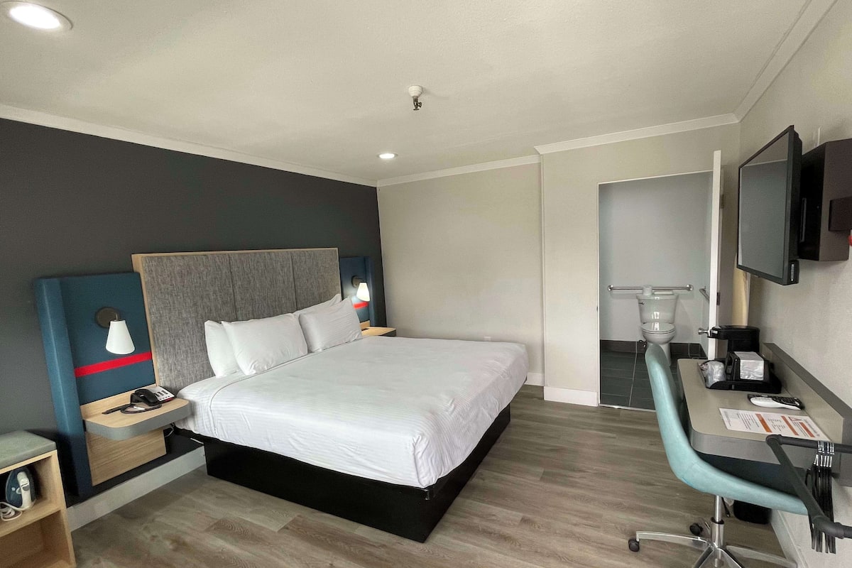 Une chambre d’hôtel comprenant un lit, une table de chevet, une lampe et un bureau avec une chaise.