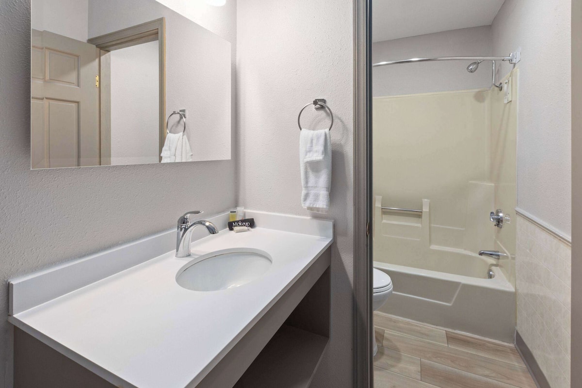 A modern bathroom with a white sink, a mirror, a towel rack, and a glass-enclosed shower area.