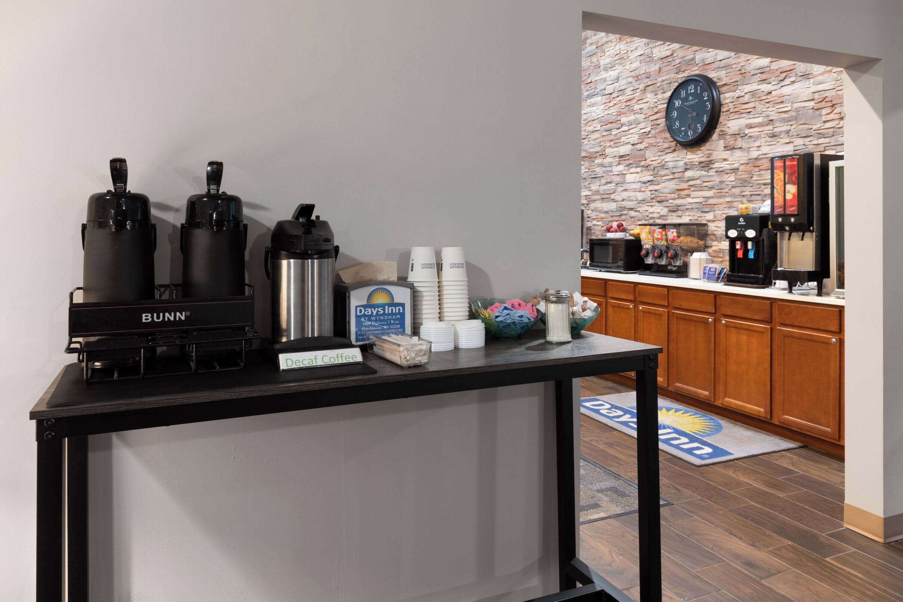 A coffee station with Bunn coffee makers, a Days Inn sign, and a clock on the wall.