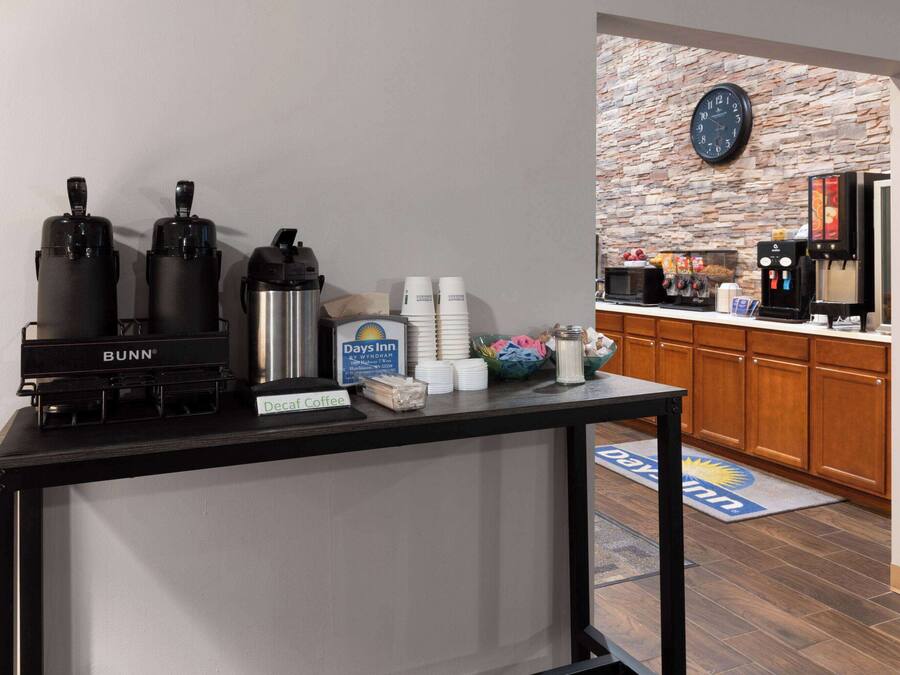 A coffee station with Bunn coffee makers, a Days Inn sign, and a clock on the wall.