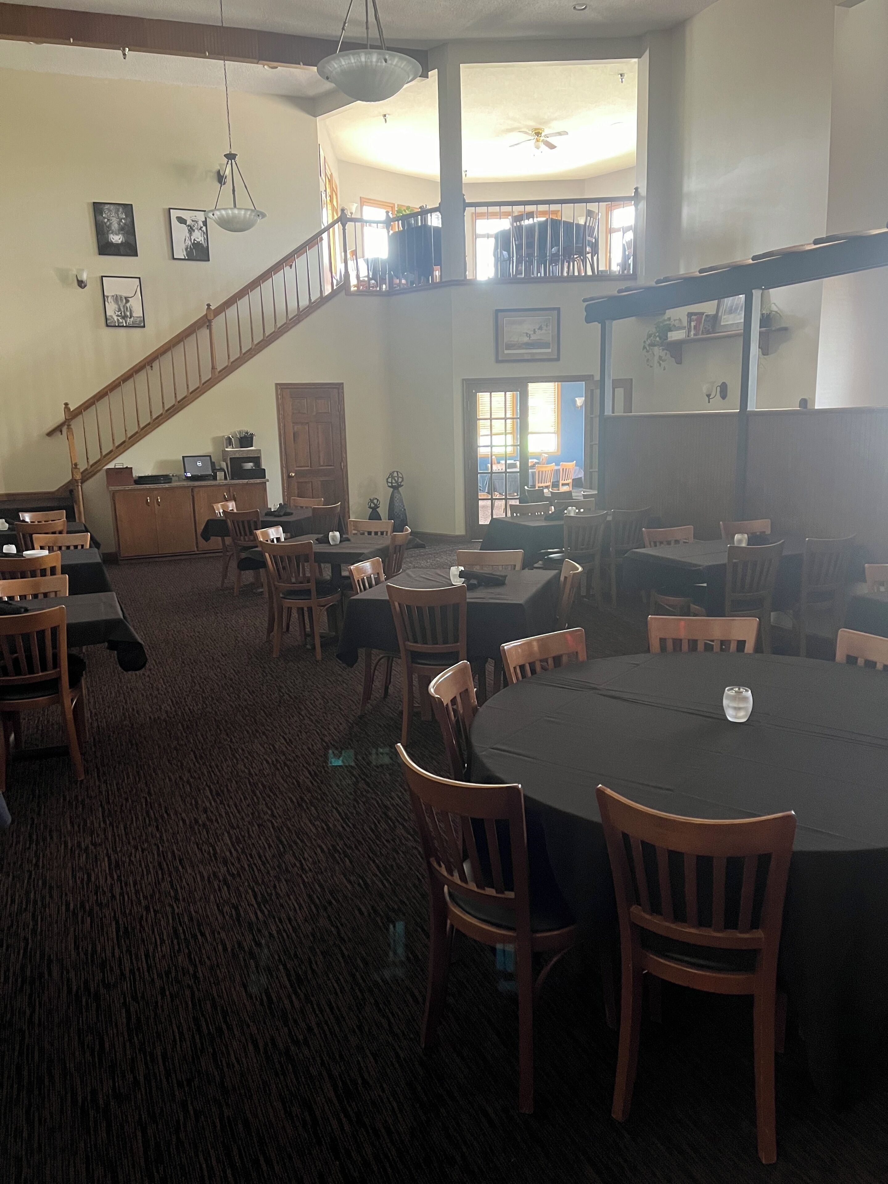 A spacious dining area with high ceilings, a staircase, and a view of the outdoors.