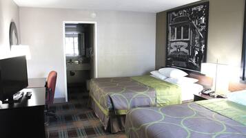 A hotel room with two beds, a desk with a computer, a TV, and a large wall mural.