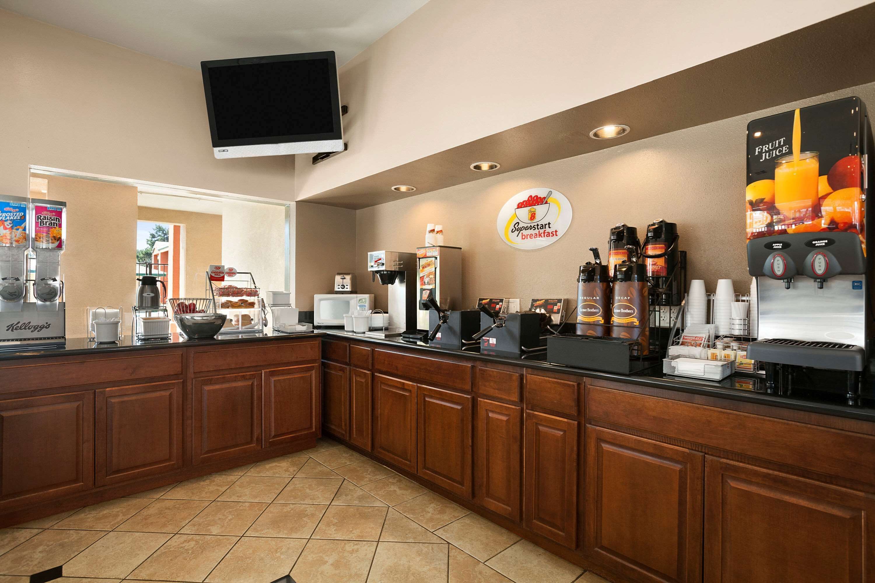 A breakfast bar with a coffee machine, a fruit juice dispenser, and a sign for 'Spoonstart breakfast'.