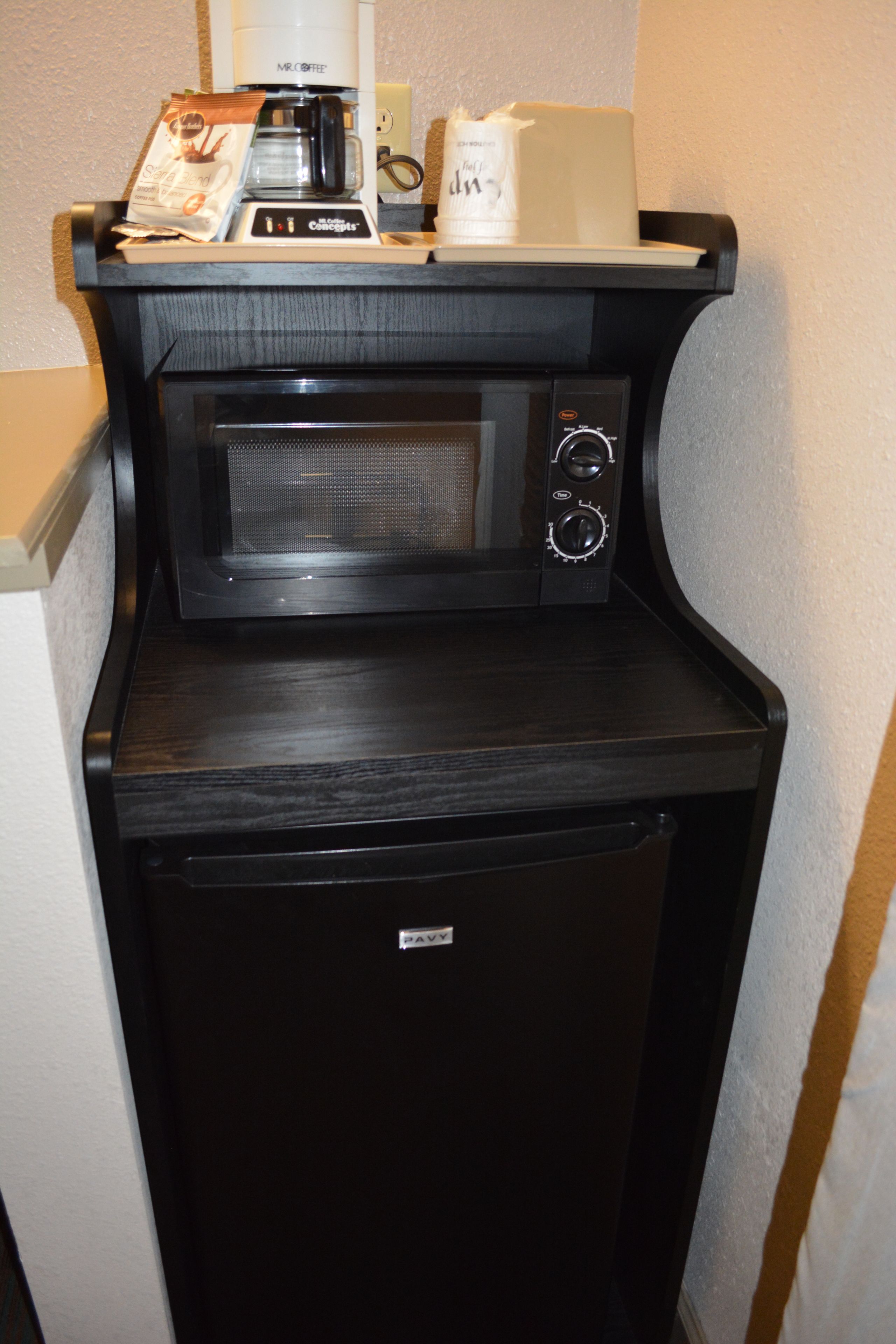 A compact kitchenette with a microwave, coffee maker, and a small refrigerator.