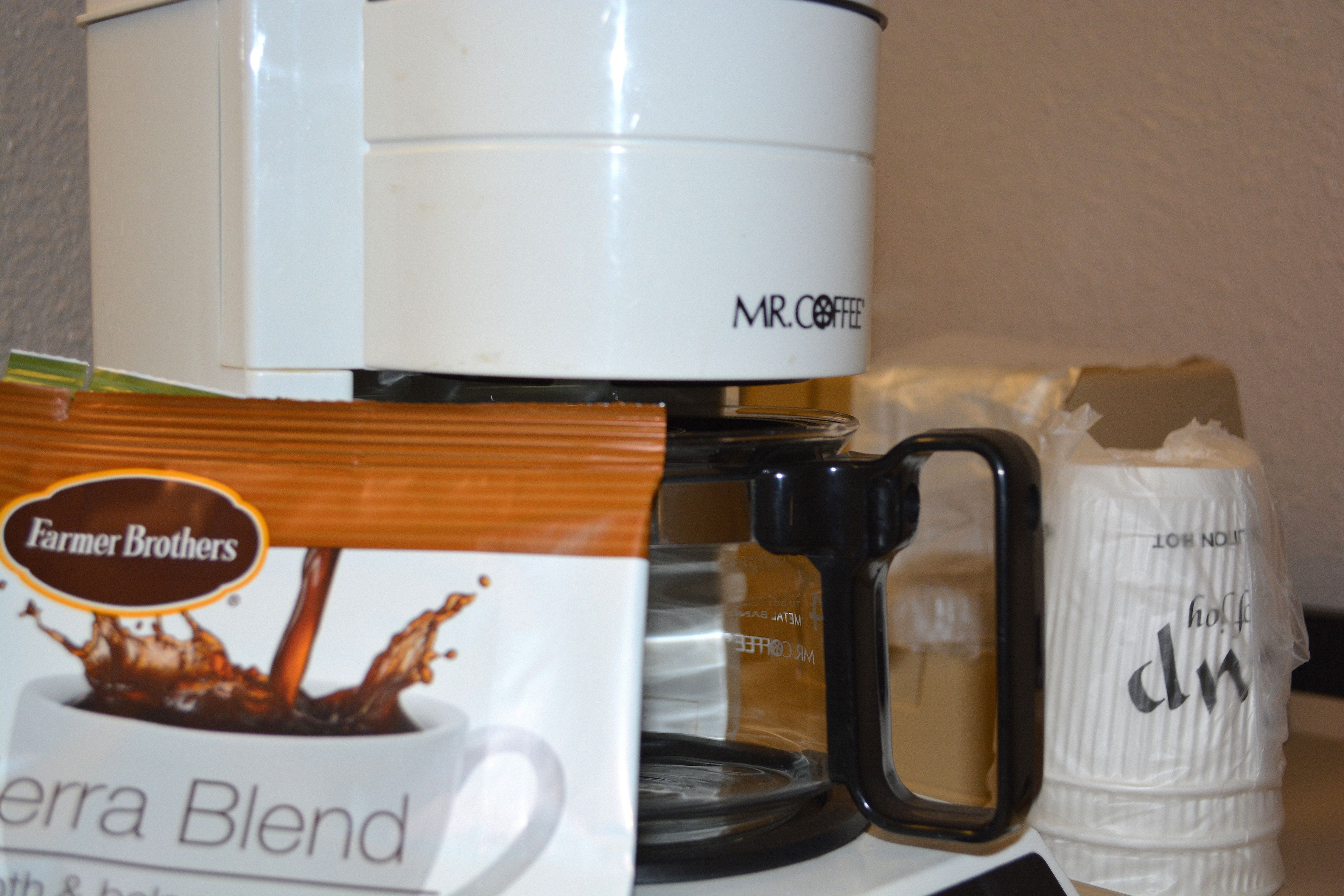 Eine Kaffeemaschine, ein Filtertütenbeutel und eine Kaffeetasse auf einem Tisch.