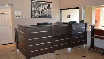 A reception desk with a framed welcome sign, a clock, and a digital display.