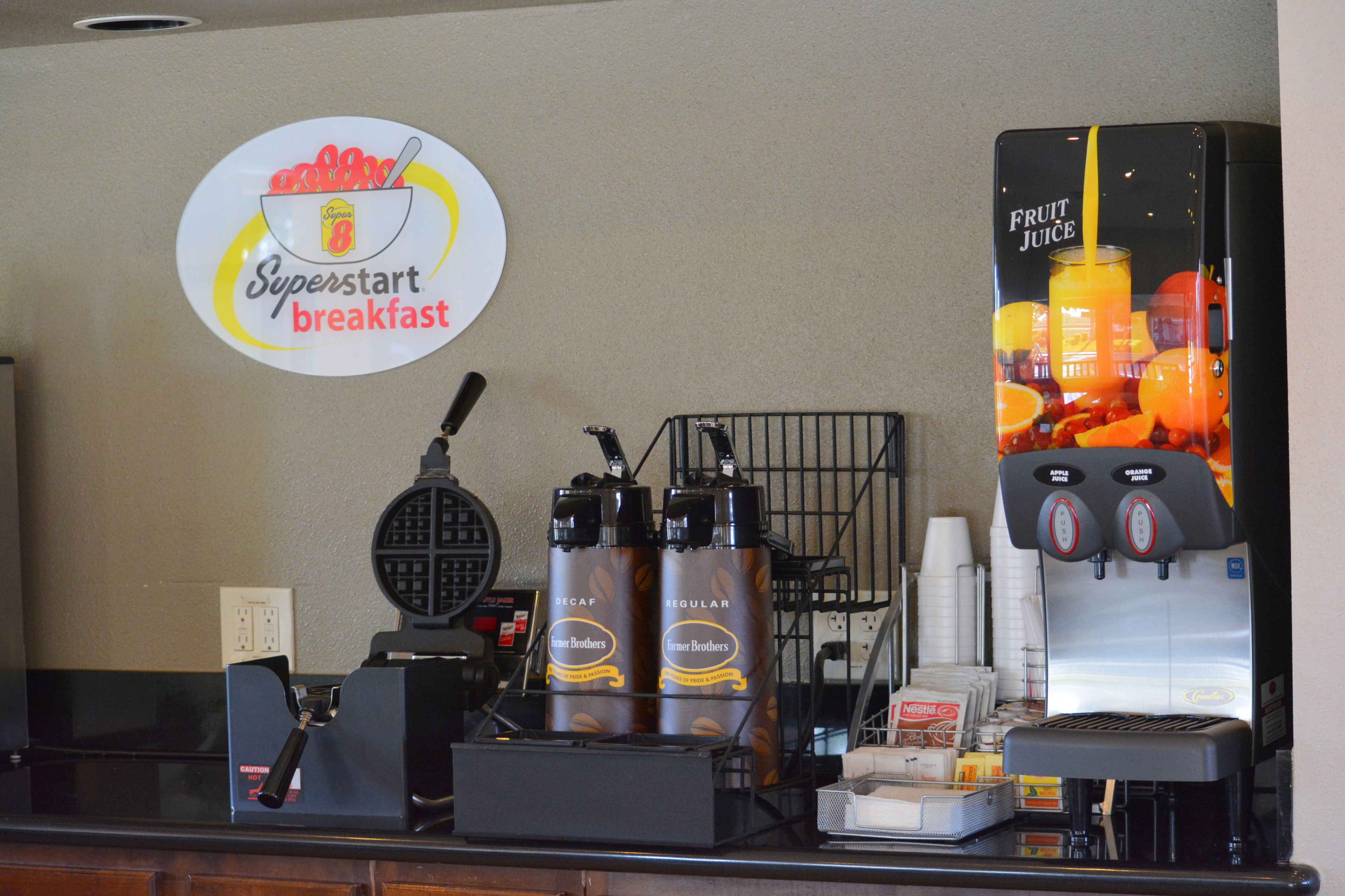 A breakfast counter with a coffee machine, decaf and regular coffee options, and a fruit juice dispenser.