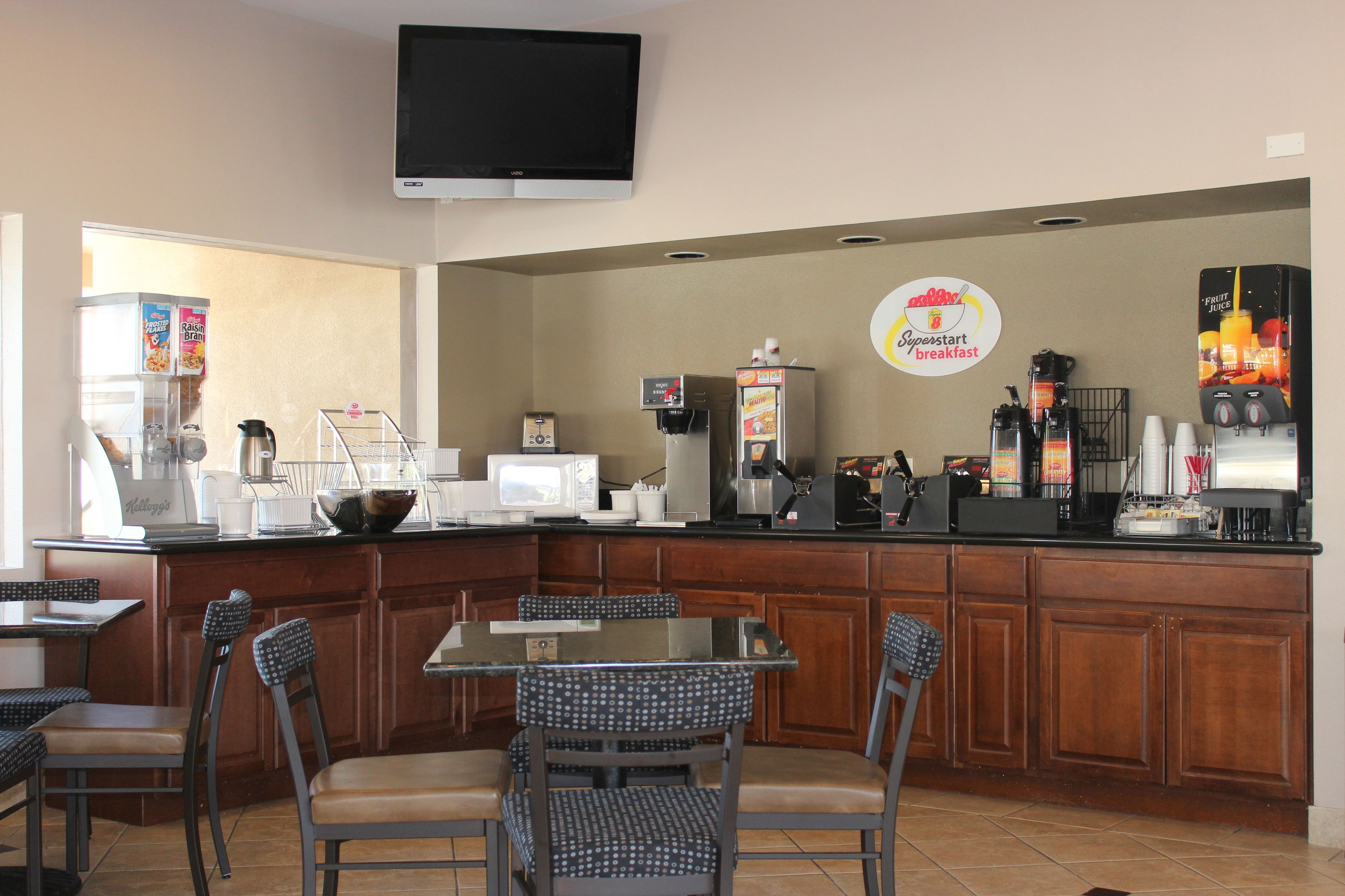 A breakfast bar with seating, a coffee machine, and a television above.