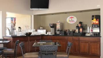 A breakfast bar with seating, a coffee machine, and a television above.