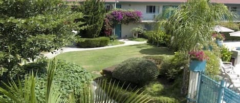 Una casa residencial con un césped cuidado, varios arbustos y una valla azul.