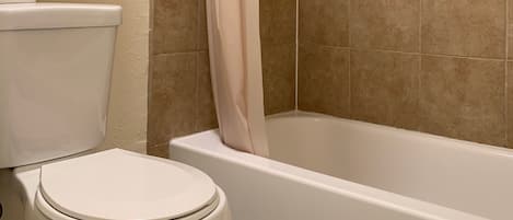 Un baño con inodoro, bañera y cortina de ducha.