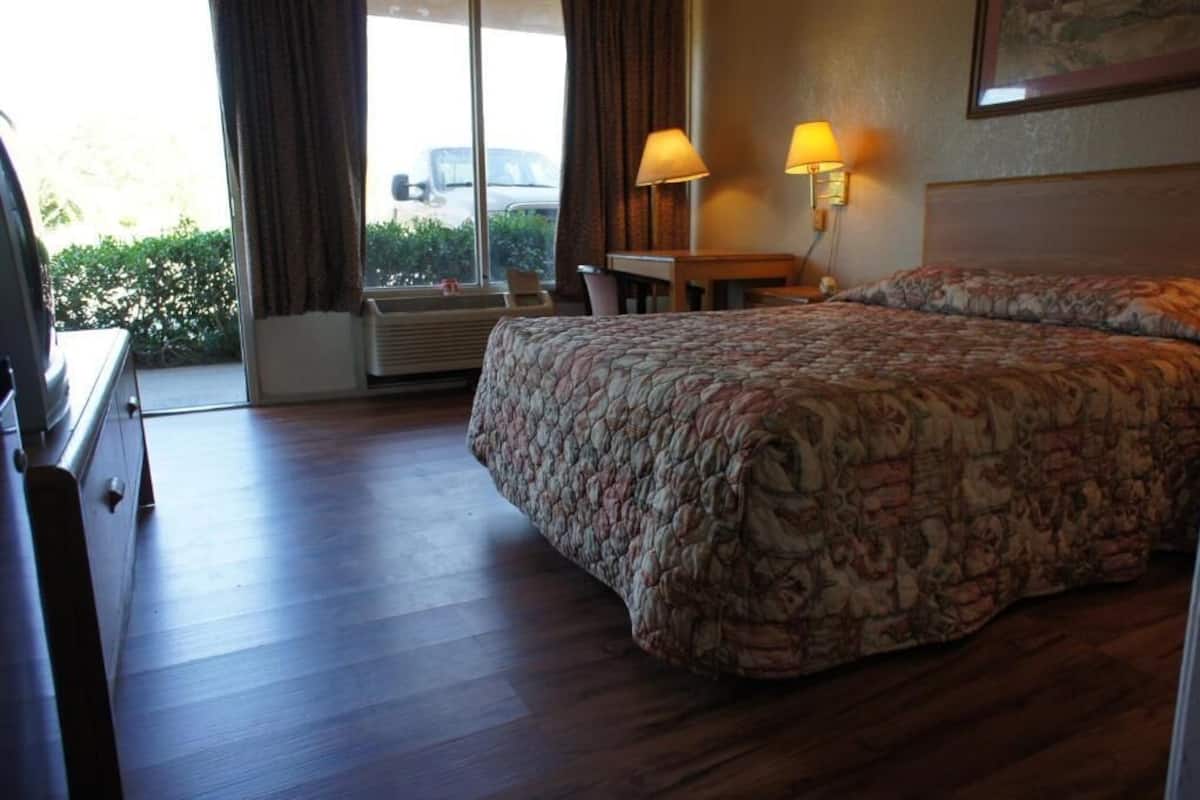 A hotel room with a bed, a desk, a chair, and a window with curtains.