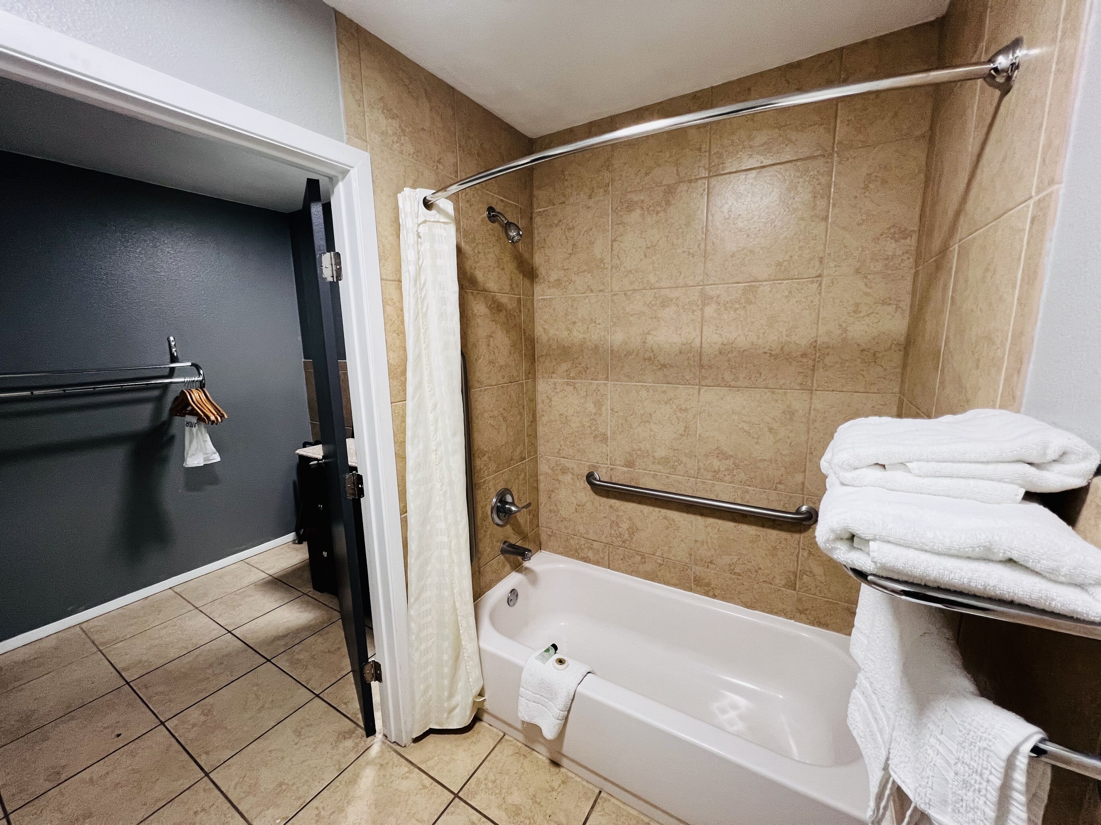Un baño con bañera, cortina de ducha, toallero y barra de apoyo.