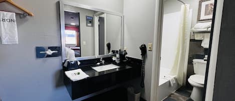 A modern bathroom with a black sink, mirror, and a shower area visible through an open door.