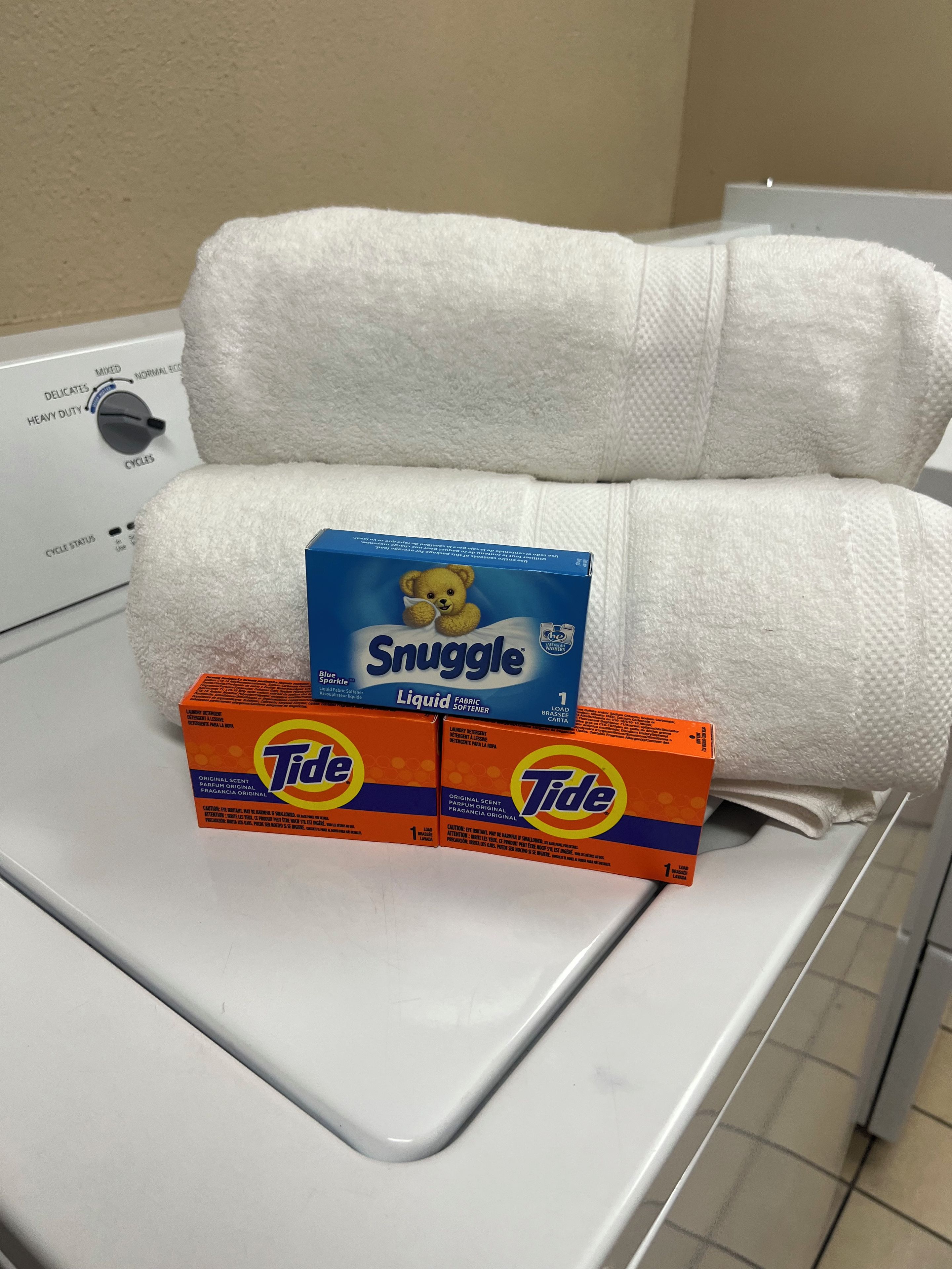 A washing machine with a white towel and two Tide detergent boxes on top.