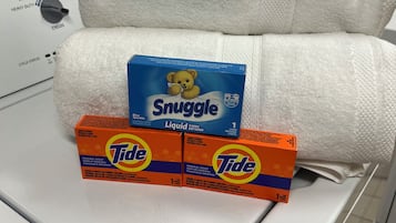A washing machine with a white towel and two Tide detergent boxes on top.