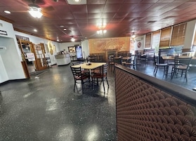 Interior de un restaurante con mostrador, mesas y sillas.