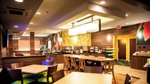 Ristorante d'hotel con diversi tavoli e sedie, un'area buffet e una cucina sullo sfondo.