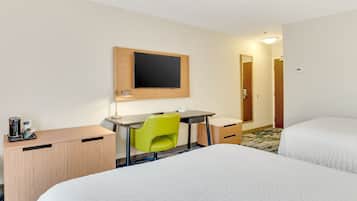 A hotel room with two beds, a desk, a chair, a flat-screen TV, and a coffee maker.