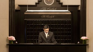 A reception desk with a clock, a chandelier, and a sign that reads "The Carlton." - The Carlyle, A Rosewood Hotel (New York)