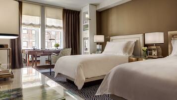 A hotel room with two beds, a desk, and a chair.