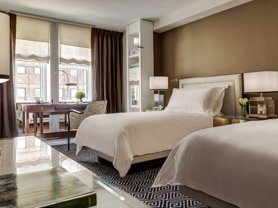 A hotel room with two beds, a desk, and a chair.