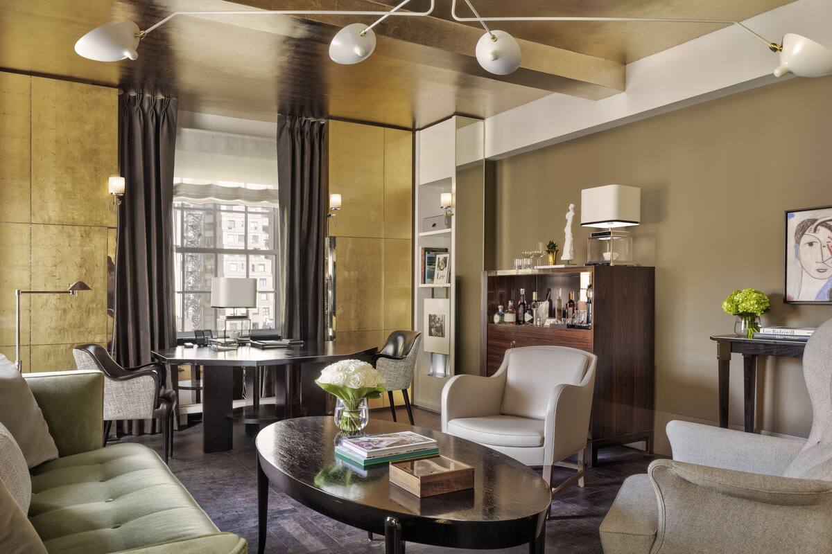 A modern living room with a round coffee table, a sofa, and a chair. There is a dining table with chairs, a bookshelf, and a lamp.
