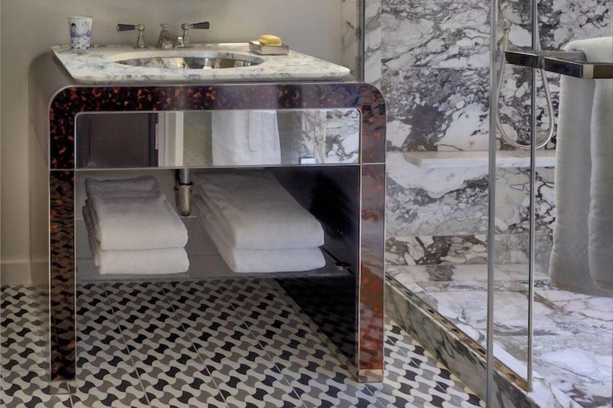 A bathroom with a marble sink, a large mirror, and a glass-enclosed shower.