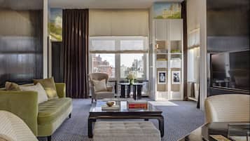 Un salon moderne avec un canapé, des fauteuils, une table basse et une vue sur la ville grâce à de grandes fenêtres.