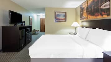 A hotel room with a large bed, a TV, a desk, and a painting on the wall.