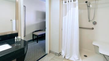 A bathroom with a shower, a sink, and a bench.